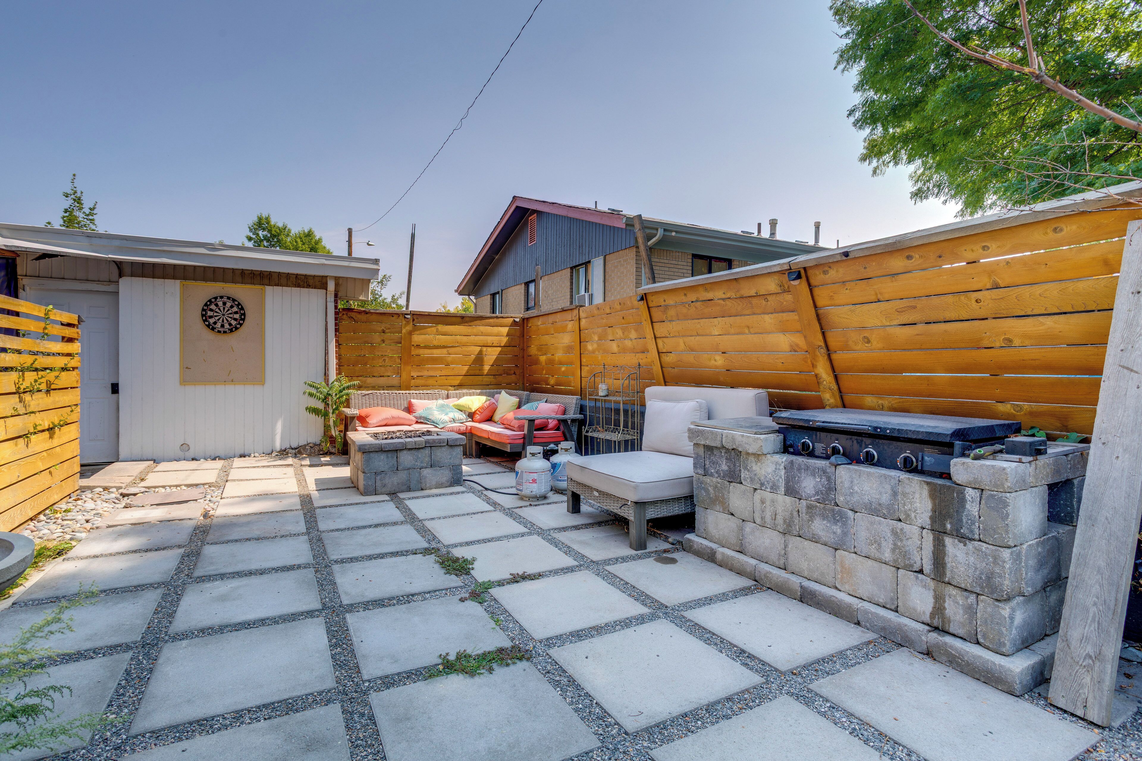 Un jardin avec un barbecue, des meubles d’extérieur et un jeu de fléchettes.
