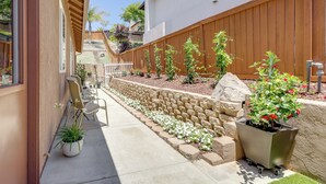 A residential backyard with a stone retaining wall, potted plants, and a wooden fence. - Private & Spacious Deluxe Rolling Hills Ranch Gem (Chula Vista)