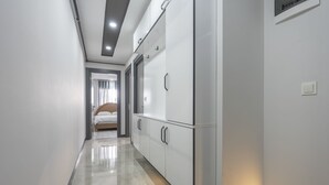 Ein moderner Hotelgang mit einem glänzenden Boden, einem Bett im Hintergrund und einem großen Schrank mit Spiegel.