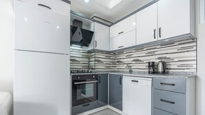 Eine moderne Küche mit weißen Schränken, einem eingebauten Backofen und einem Geschirrspüler.