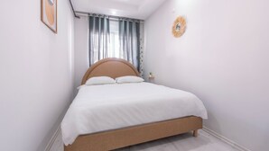 Ein Schlafzimmer mit Bett, Vorhängen, einer Wanduhr und einer kleinen Pflanze.