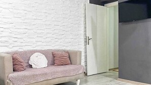 Un salon avec un canapé, un tapis à motifs et un mur en briques blanches.