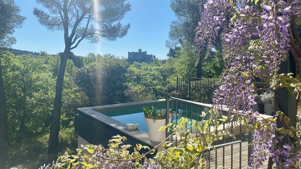 Un espace piscine offrant une vue sur une forêt et un bâtiment en arrière-plan.