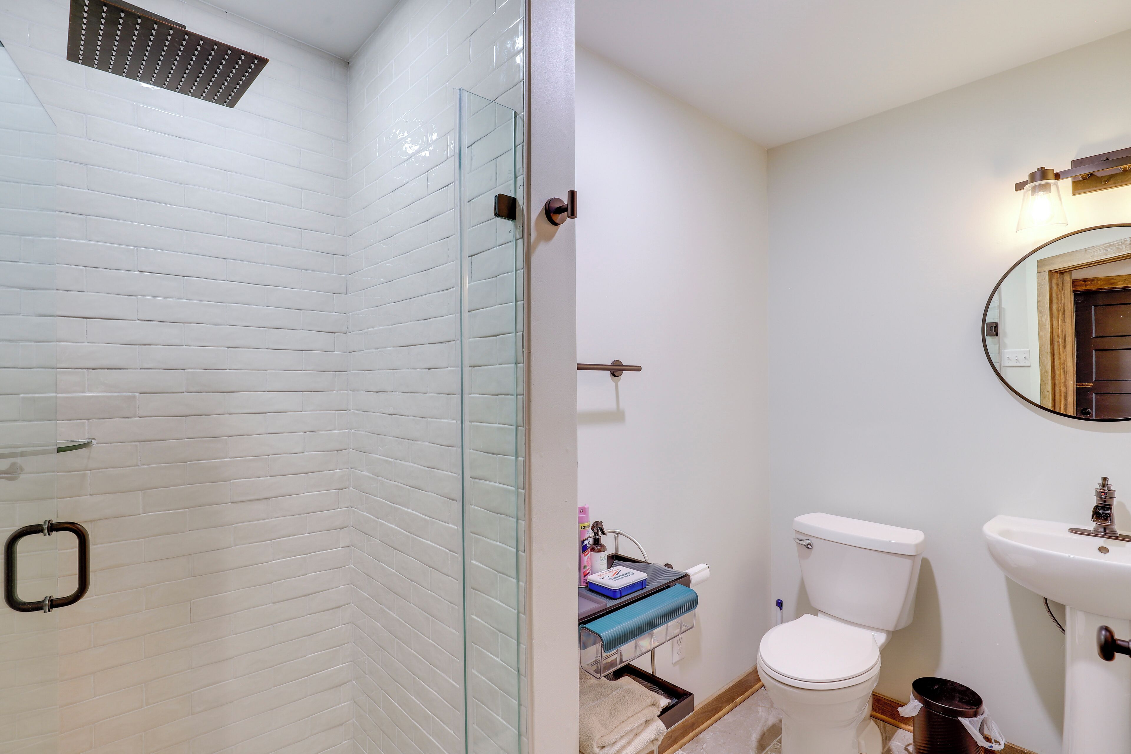 Une salle de bain avec une douche à parois de verre, des toilettes, un lavabo et un miroir.