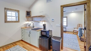 A compact kitchen with a sink, microwave, and refrigerator, wooden flooring, and a view into a living area with a chair and a window. - 2 Blocks to Appalachian Trail! Couple's Retreat (Hot Springs)
