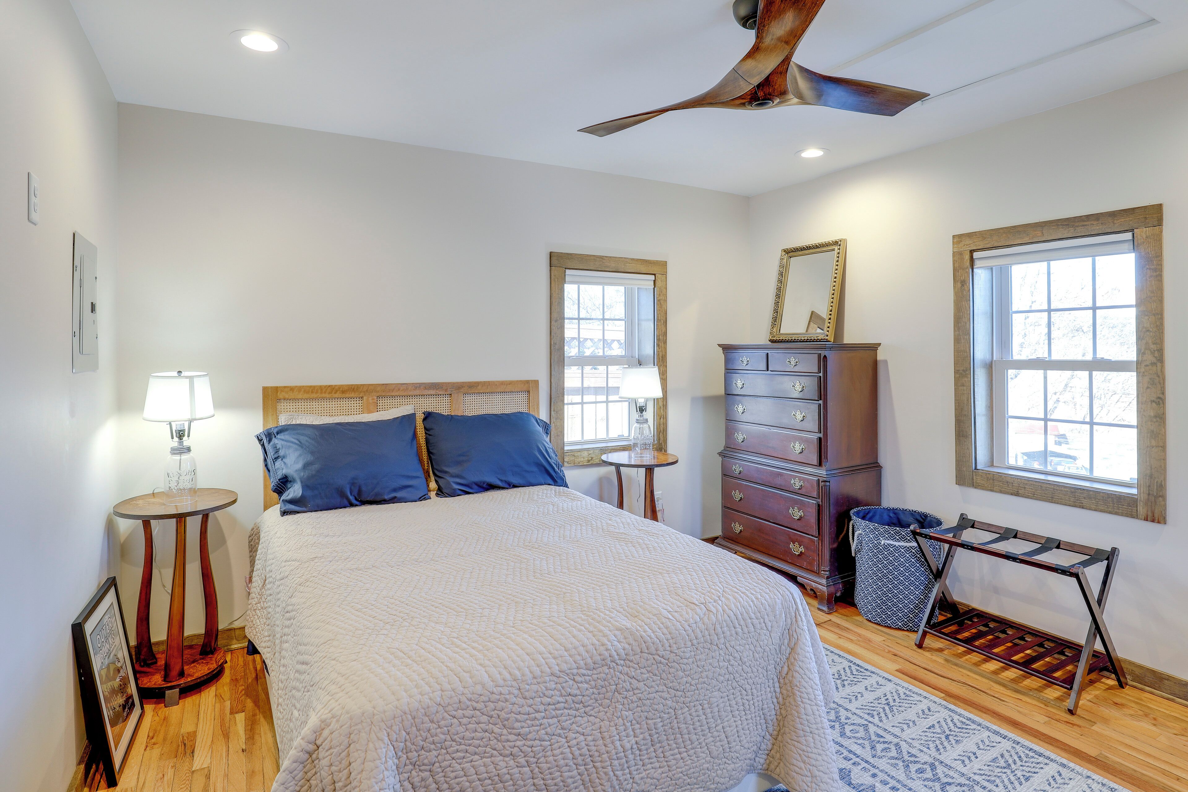 A bedroom with a bed, dresser, lamp, and a ceiling fan.