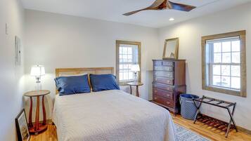 A bedroom with a bed, dresser, lamp, and a ceiling fan.