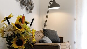 Un salon avec un canapé marron, un lampadaire noir et un vase rempli de tournesols.
