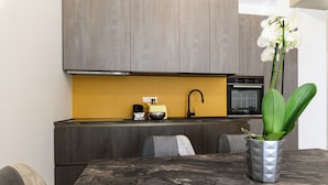 A modern kitchen with dark cabinets, a yellow backsplash, and a marble countertop. - Rome House Jambokella Apartment in the historic district of Monteverde  (Roma)