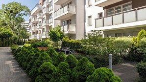 A multi-story residential building with balconies, a paved walkway, and well-maintained greenery. - Lion Apartments - The Wave (Gdansk)