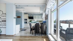 A modern kitchen with a dining area, large windows, and a view of the city. - Lion Apartments - The Wave (Gdansk)
