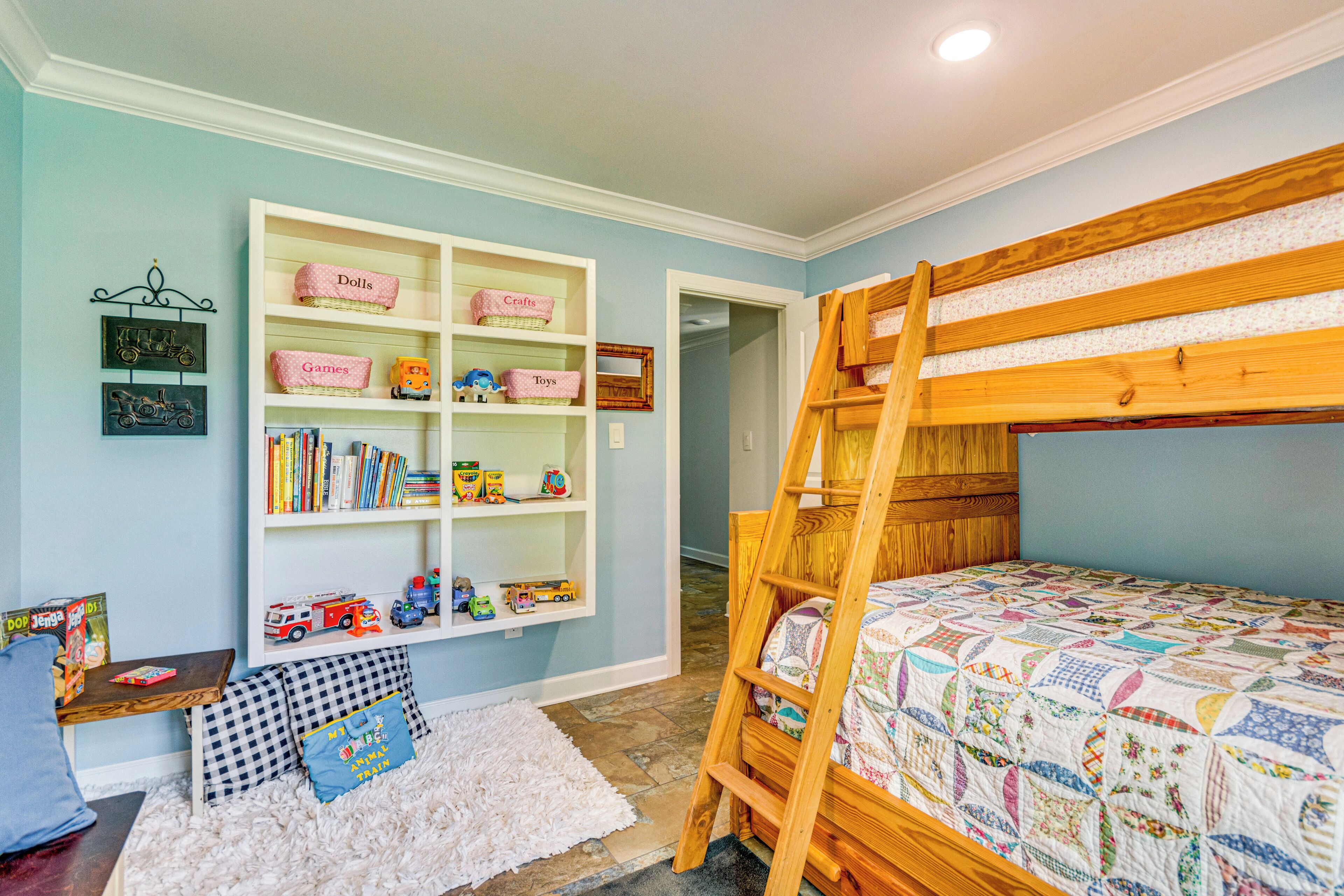 A child's room with a bunk bed, a bookshelf, and a play area.