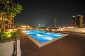 A rooftop swimming pool with surrounding greenery and modern buildings in the background. - Travel Friendly Small Studio in the Heart of Dubai (Dubai)