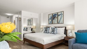 A modern hotel room with a wooden bed, a gray sofa, and a glass coffee table. - Comfy studio in Heart of Waikiki! Quick walk to beach, close to Ala Moana! (Honolulu)