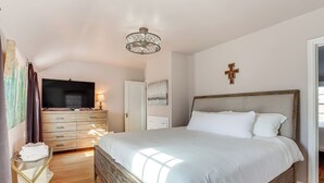 A bedroom with a large bed, wooden dresser, and a television. - Half-mi to Unc: Historic Dtwn Greeley Home (Greeley)