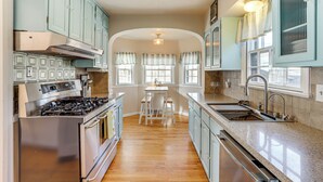 A kitchen with light blue cabinets, a stainless steel stove, and a wooden floor. - Half-mi to Unc: Historic Dtwn Greeley Home (Greeley)