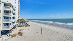 Un hôtel situé en bord de mer, doté de nombreux balcons, d’un espace piscine et d’une plage de sable.