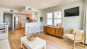 Une cuisine moderne avec des meubles blancs, des appareils en acier inoxydable et un îlot central doté de tabourets.
