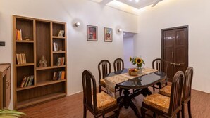 Un coin repas comprenant une table ronde, six chaises, une bibliothèque et des tableaux encadrés accrochés au mur.