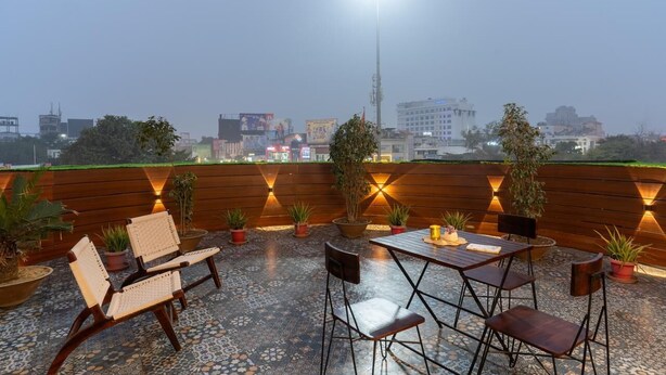 Une terrasse sur le toit, dotée de sièges en bois, de plantes en pot et d’une table avec une bougie.