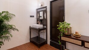 Une salle de bain avec un lavabo blanc, un meuble-lavabo en bois foncé et une plante en pot.