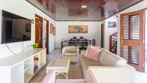 Ein Wohnzimmer mit Fernseher, einer Couch und einem Essbereich.