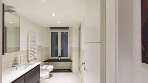 A modern bathroom with a white sink, dark wooden cabinets, a large mirror, and a toilet with a towel rack. - Galea Studio by Wonderful Italy (Genova)