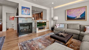 A spacious living room with a fireplace, a large TV, and a comfortable sofa. - 3 Miles to Resort | Hot Tub | Fireplace | EV Charger | Great for Groups (Winter Park)