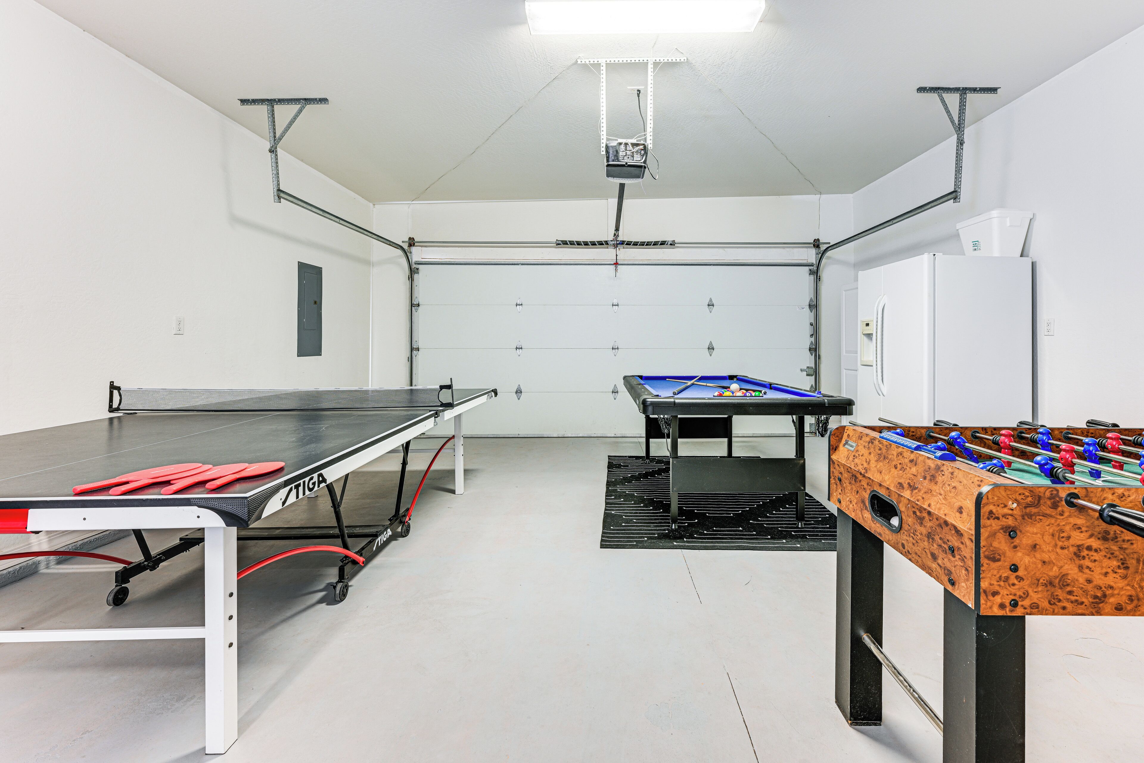 A room with a ping pong table, foosball table, and a pool table.