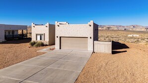 A modern house with a garage, a driveway, and a desert landscape in the background. - 4 Mi to Lake Powell: Retreat w/ Game Room! (Page)