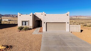 A modern house with a garage, a driveway, and a desert landscape in the background. - 4 Mi to Lake Powell: Retreat w/ Game Room! (Page)