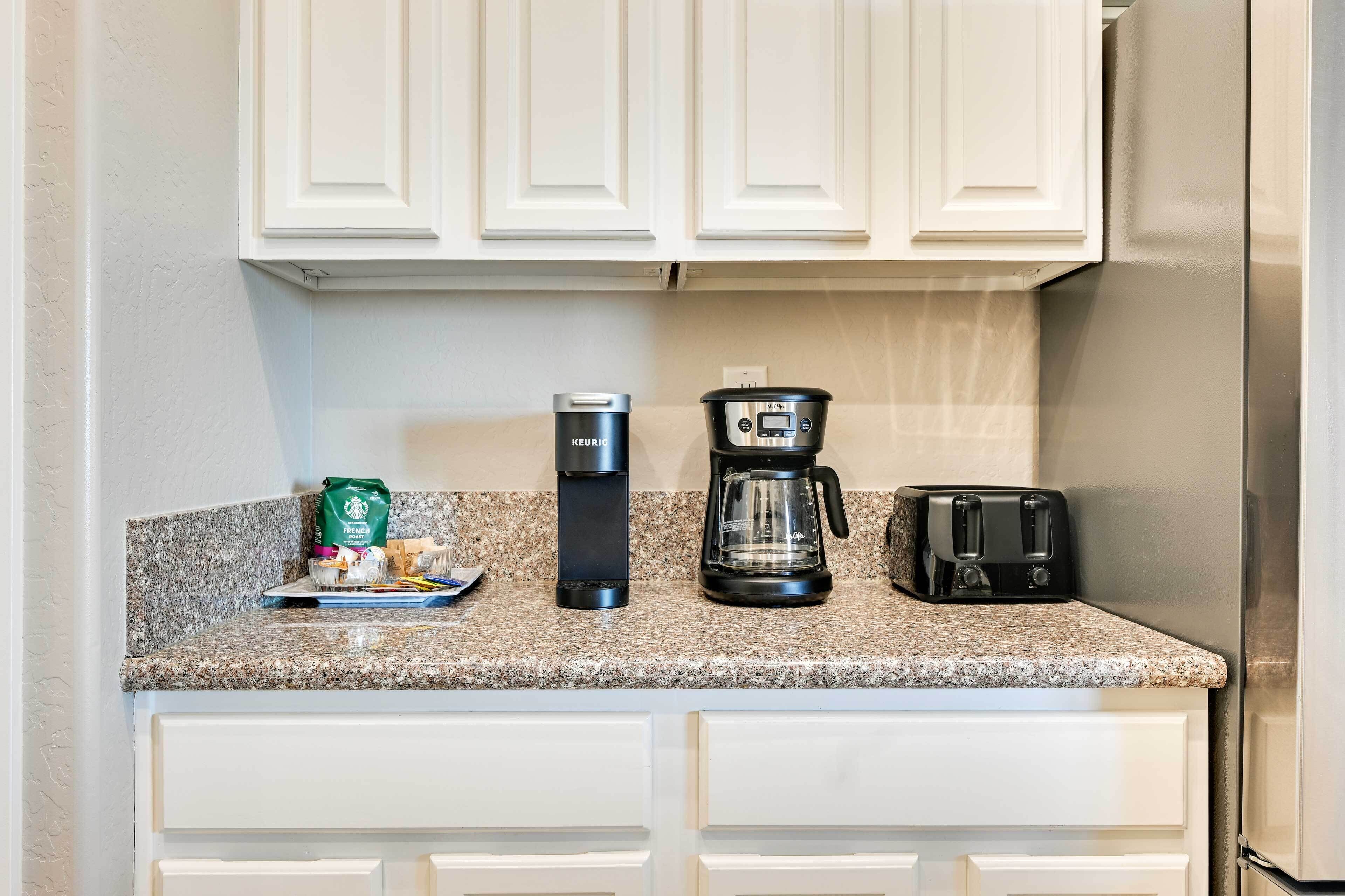 A kitchen with white cabinets, a coffee maker, a toaster, and a bag of coffee.