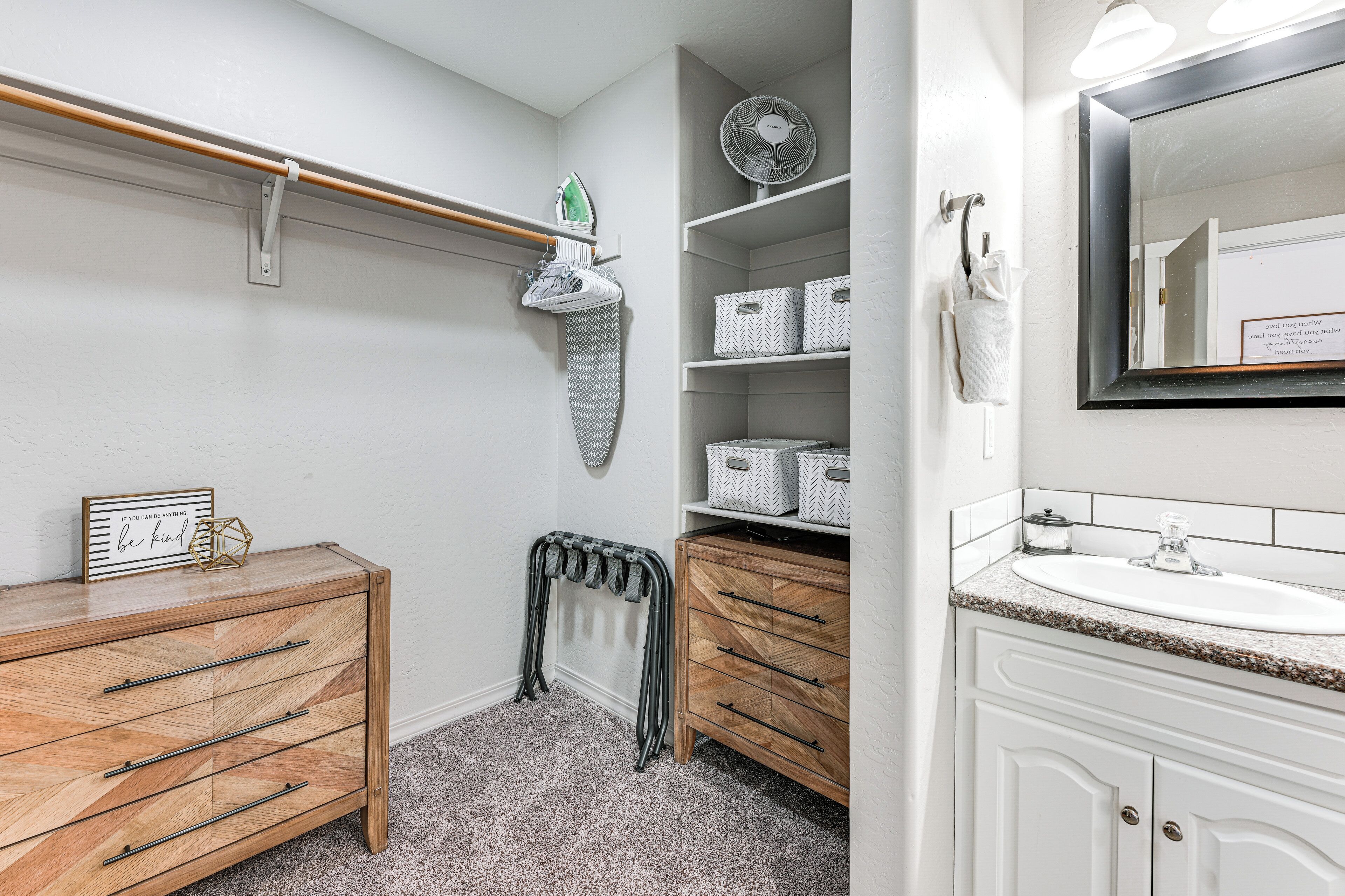 Une salle de bain avec un meuble-lavabo en bois, un radiateur mobile, un miroir et des étagères de rangement.