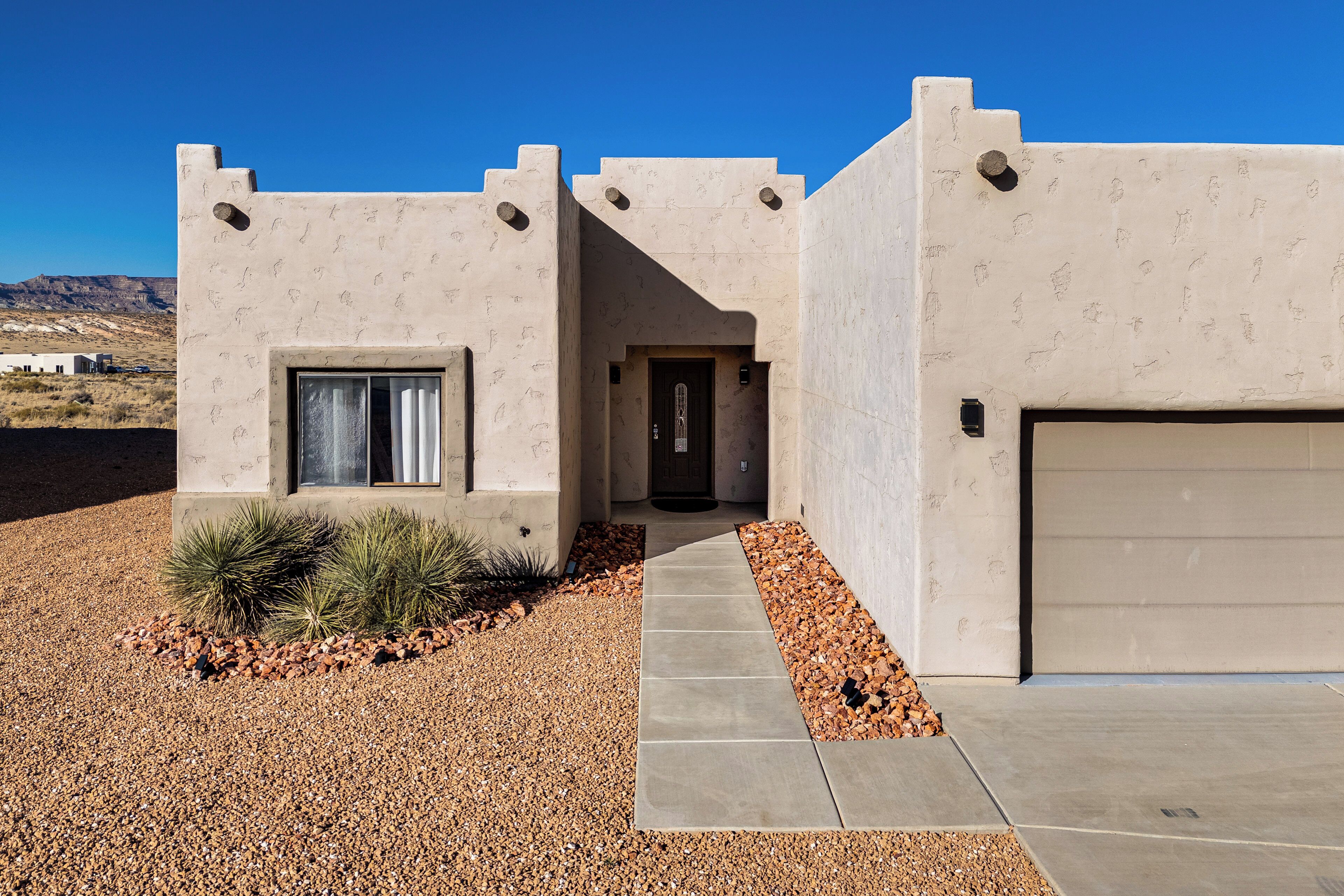 A modern house with a concrete facade, a garage, and a gravel driveway.