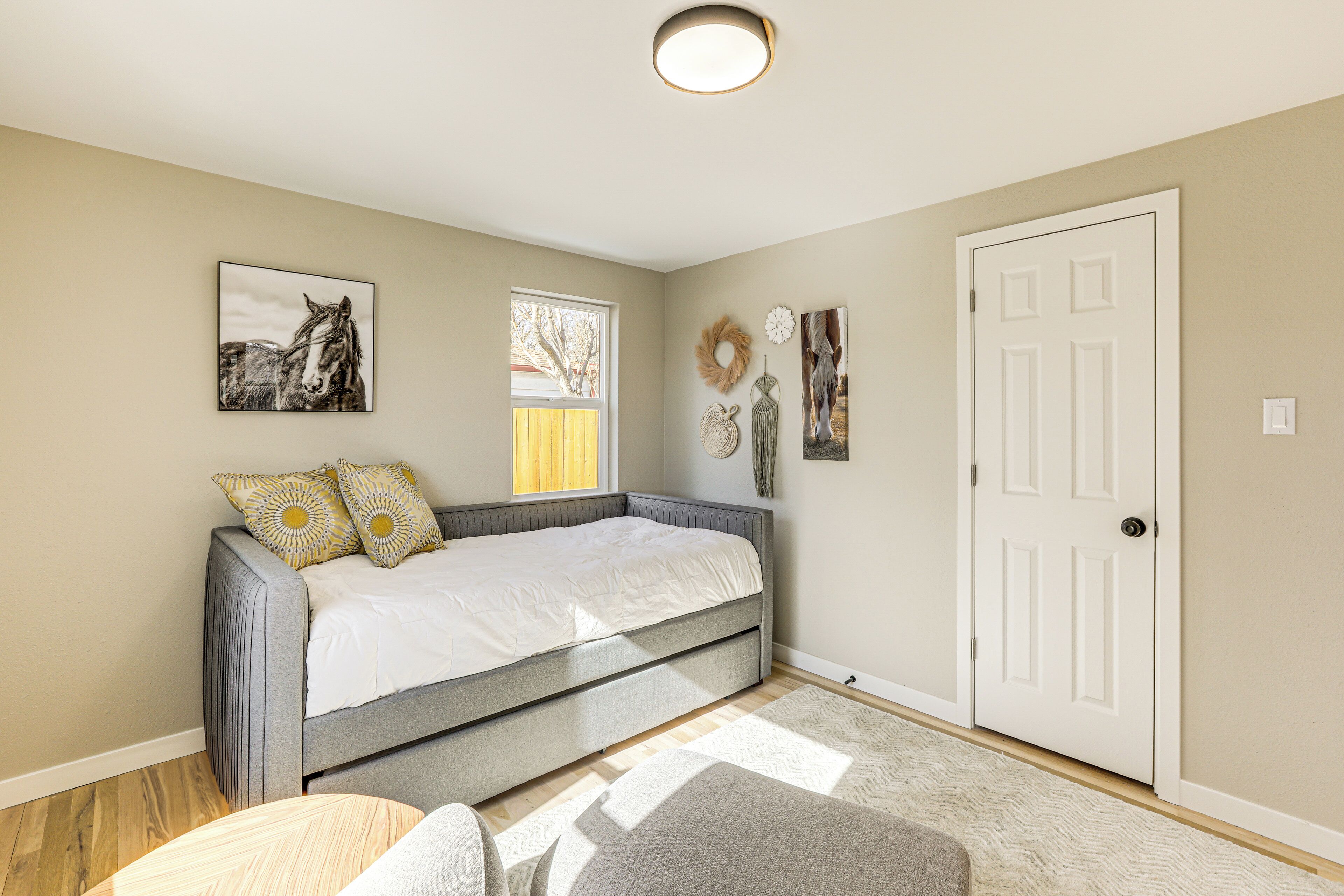 A bedroom with a bed, a window, a door, and wall decorations.