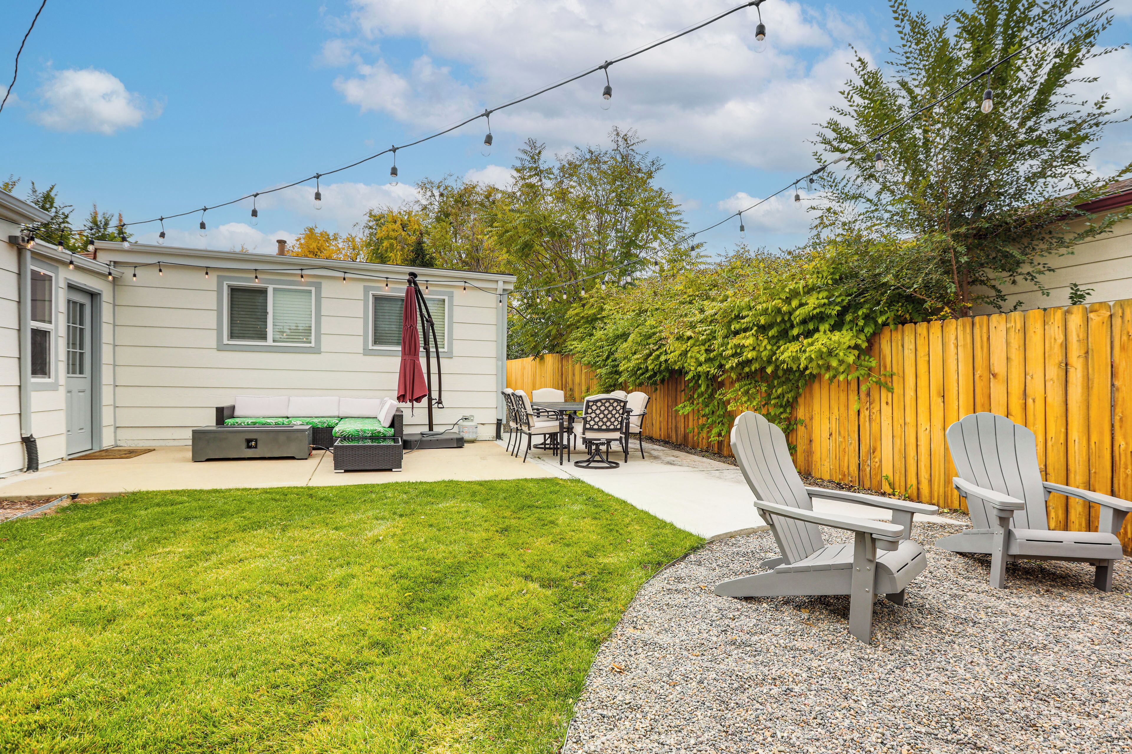 Un jardin avec une terrasse, du mobilier d’extérieur et une clôture en bois.