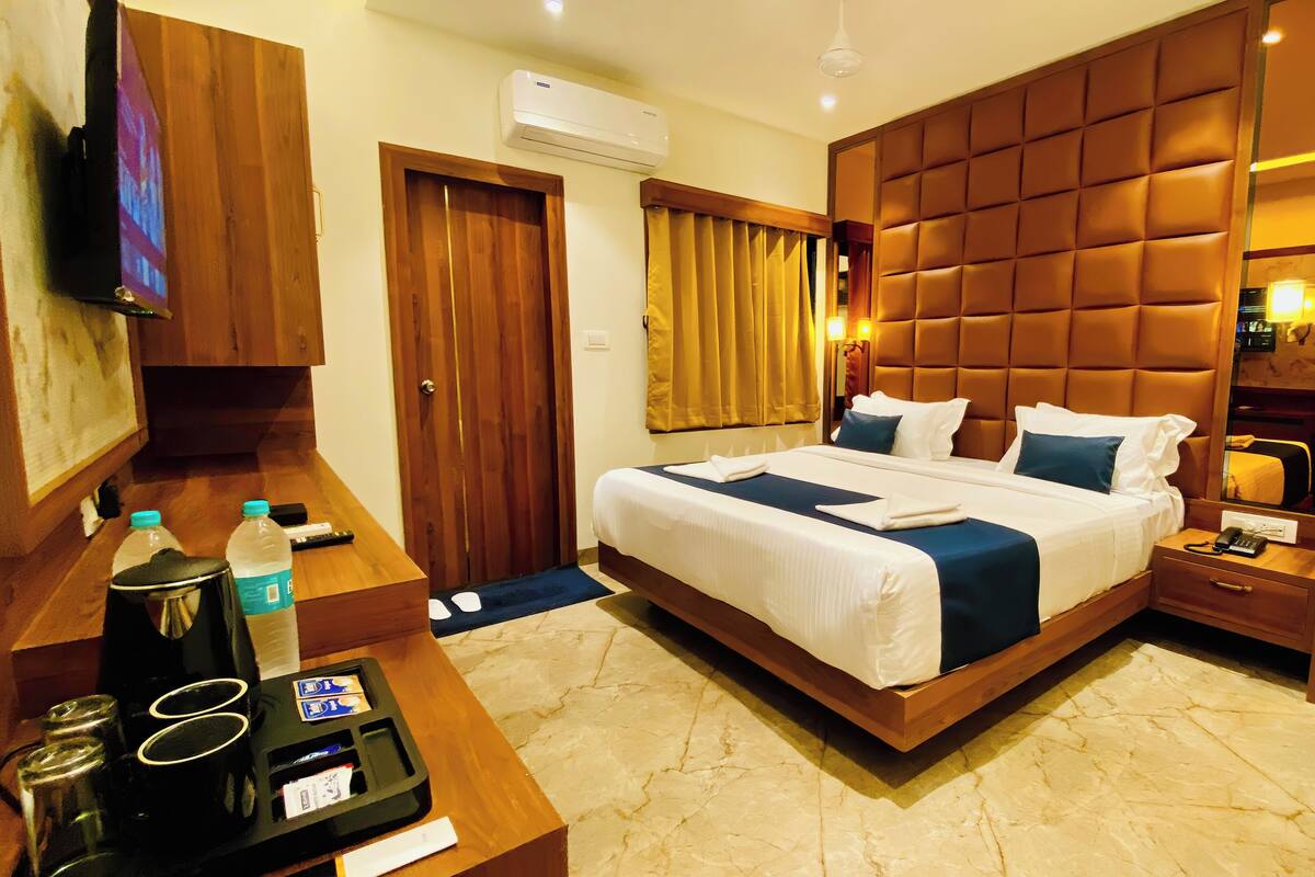 A hotel room with a bed, bedside table, chair, desk, and a mirror.