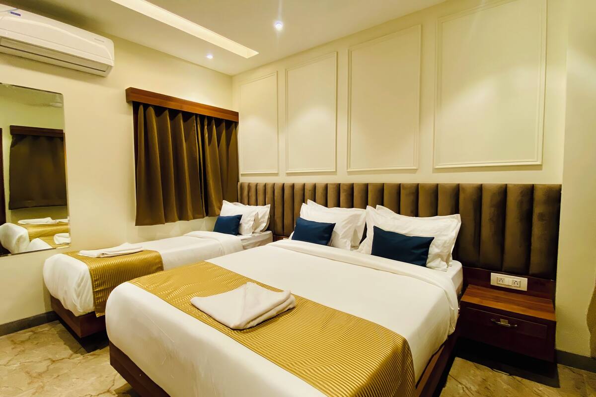 A hotel room with two beds, a large mirror, a wooden headboard, and a bedside table.