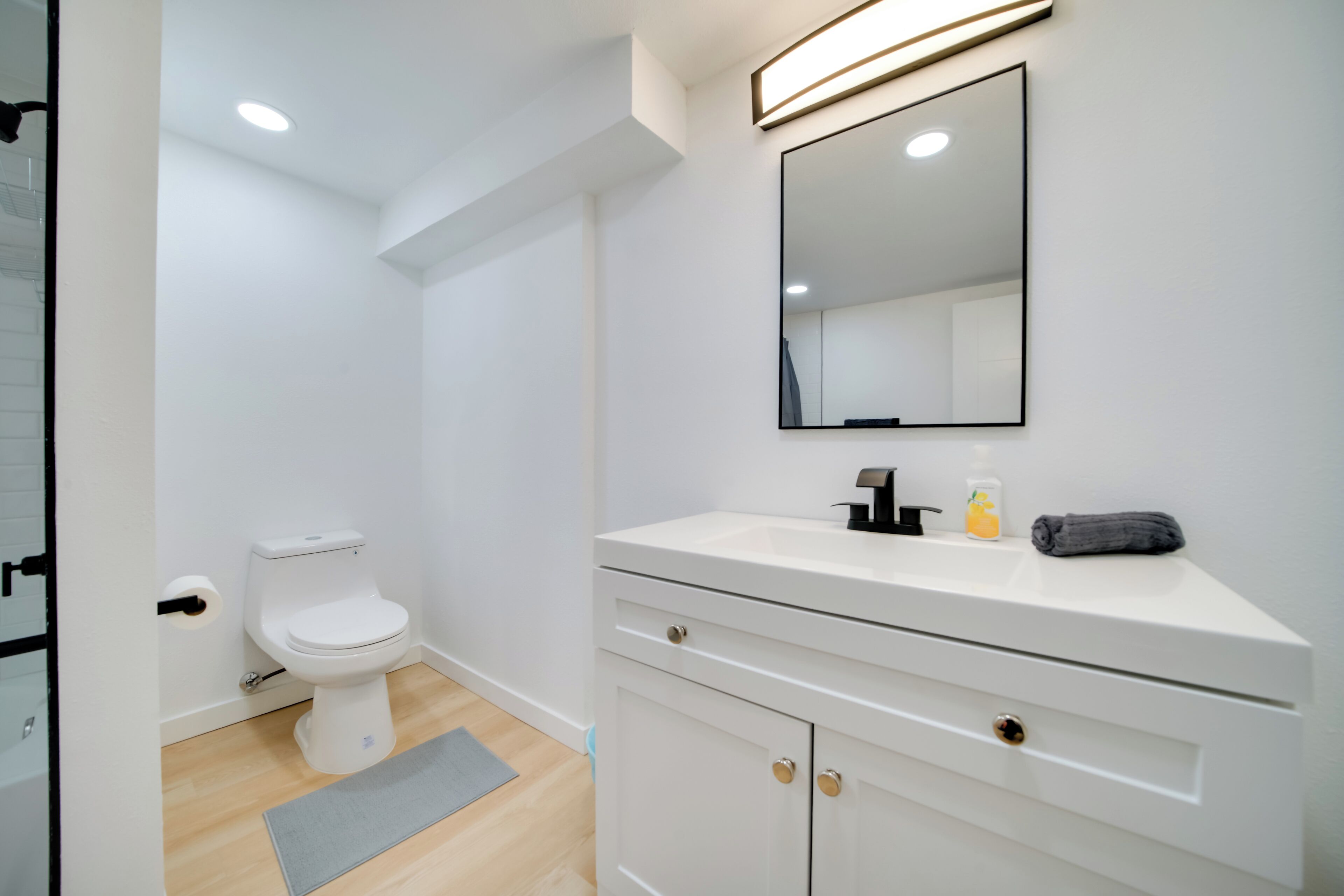 Un bany modern amb un vàter blanc, un lavabo amb un mirall a sobre i una tovallola al taulell.