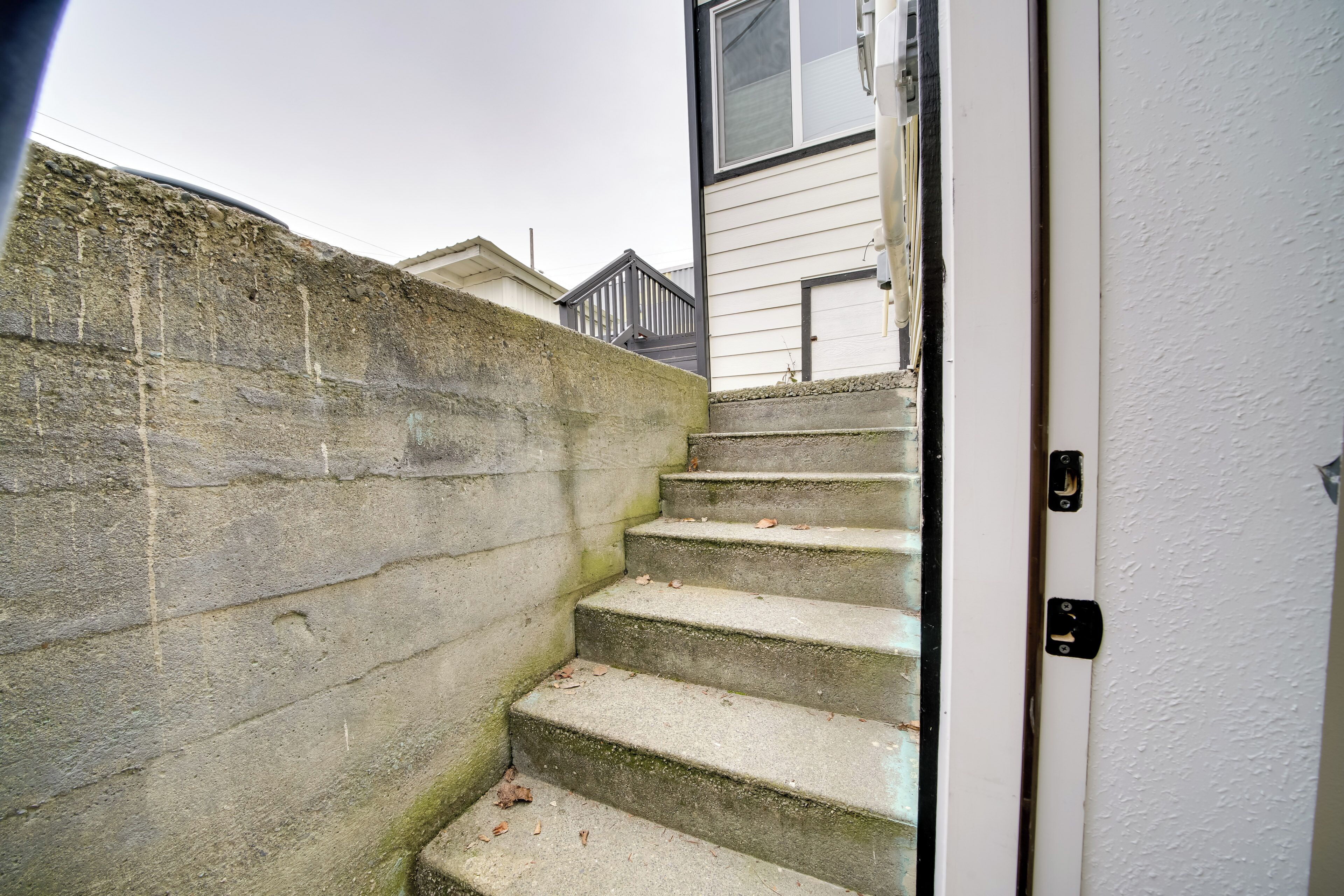 A concrete staircase leading to a white door with a black handle.