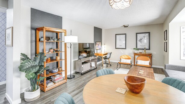 A modern living room with a round wooden table, a bookshelf, a dining area, and a large plant. - Close to Downtown & Parks: Modern Anchorage Home (Anchorage)