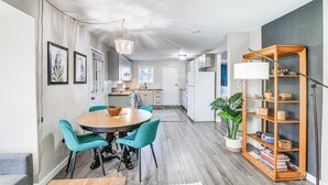 A modern kitchen with a dining area, featuring a wooden table, teal chairs, and a bookshelf. - Close to Downtown & Parks: Modern Anchorage Home (Anchorage)