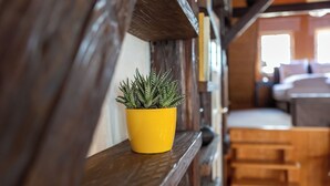 A yellow potted plant on a wooden shelf in a room with a bed and a staircase. - Loft with sauna and fireplace (Schlitz)