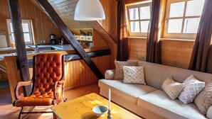 A cozy cabin interior with a wooden dining table, a cushioned chair, a sofa, and a kitchen area with a sink and cabinets. - Loft with sauna and fireplace (Schlitz)