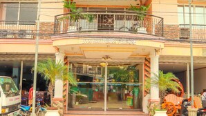 A hotel entrance with a covered entrance, potted plants, and a vehicle parked outside. - Northomes Pensione by HiveRooms (Bogo)