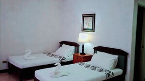A hotel room with two single beds, a ceiling light, a framed picture on the wall, and a door to the right. - Northomes Pensione by HiveRooms (Bogo)
