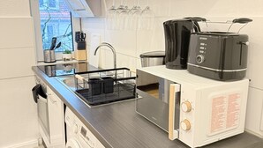 A modern kitchen with a built-in washing machine, a toaster, and a hanging wine rack. - Apartment Bremen Neustadt (Bremen)