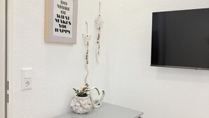 A modern bedroom with a grey dresser, a wall-mounted TV, and a motivational quote. - Apartment Bremen Neustadt (Bremen)