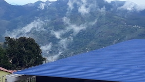 Un paysage de montagne avec un bâtiment au toit bleu au premier plan.