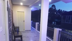 Un balcon fermé avec un sol carrelé, une porte et une table avec des chaises.